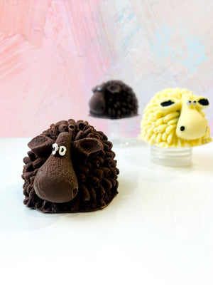 Open image in slideshow, QUEST XO Sheepy Hot Cocoa Bomb: 3 chocolate sheep cocoa bombs. Right at the back, blurry brown sheep. Centre right is a yellow sheep. Foreground left is a brown sheep.
