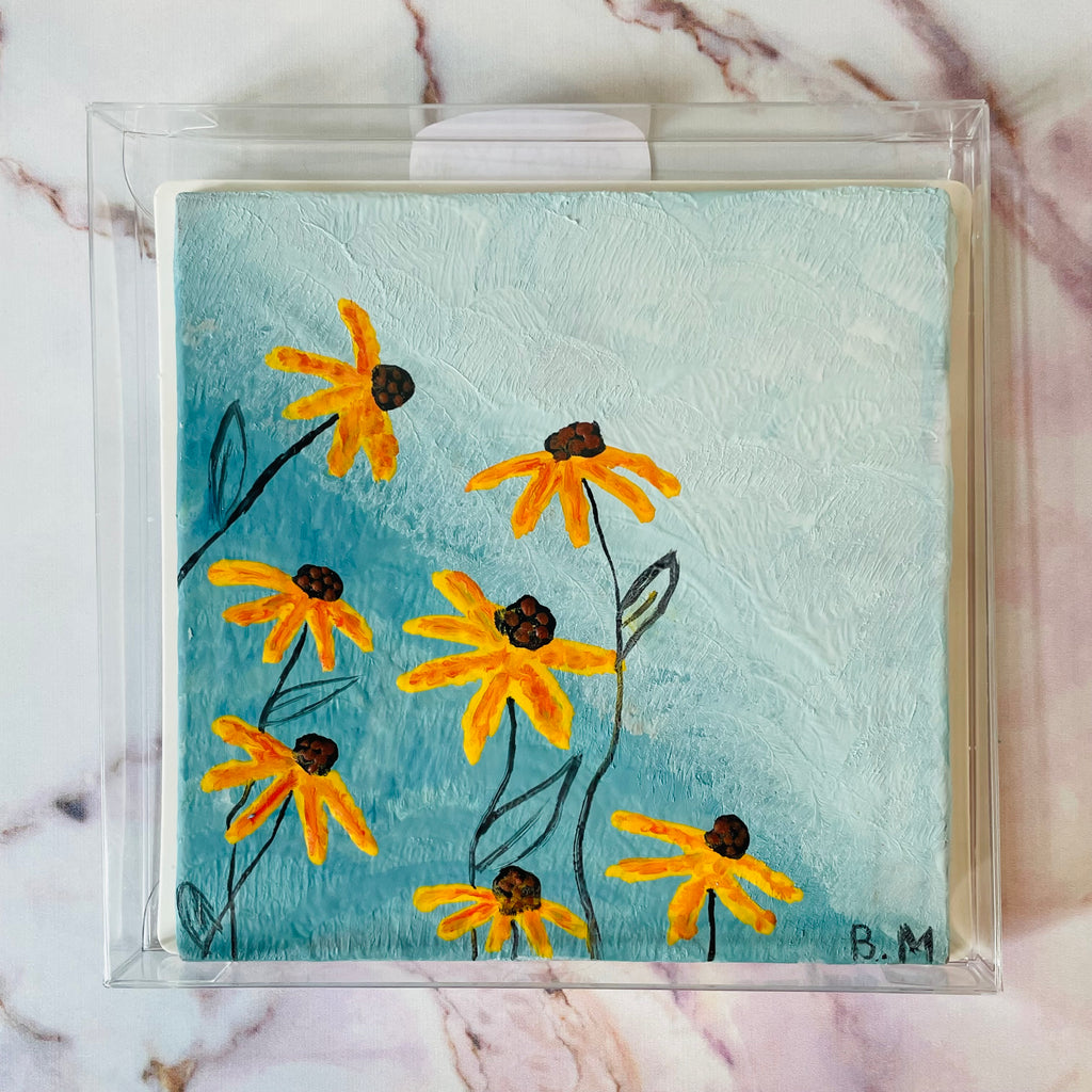 QUEST XO Sunny Spring Painting: A painting of orange flowers with black stems on a blue background packed in a transparent pack and placed on a marble background.