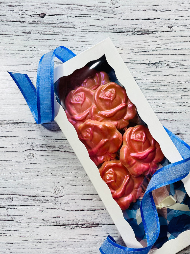 QuestXO Rose Chocolate Bouqet. The picture has a box with blue ribbons on the corner, and a bouquet of chocolate flowers inside it.