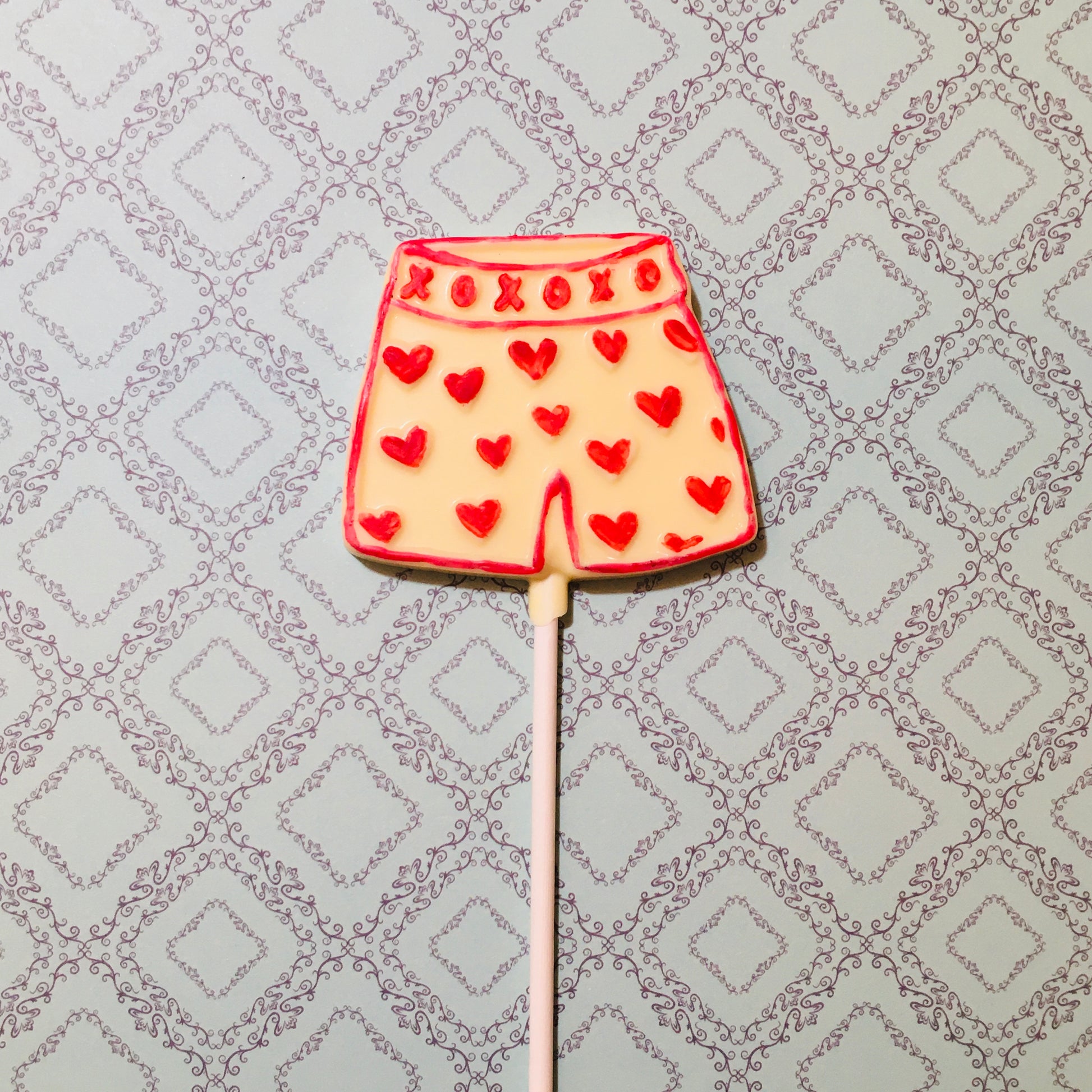 QUEST XO Cheekly Lolly: Boxer shorts lolly with red hearts on an intricate background.
