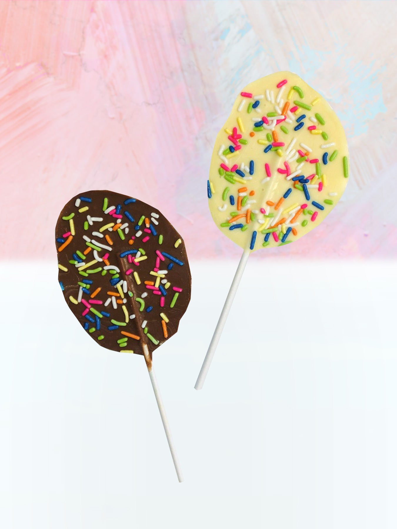 QUEST XO Egg Lolly: Brown and yellow lolly with colourful sprinkles and white stick placed on a pink and white background.
