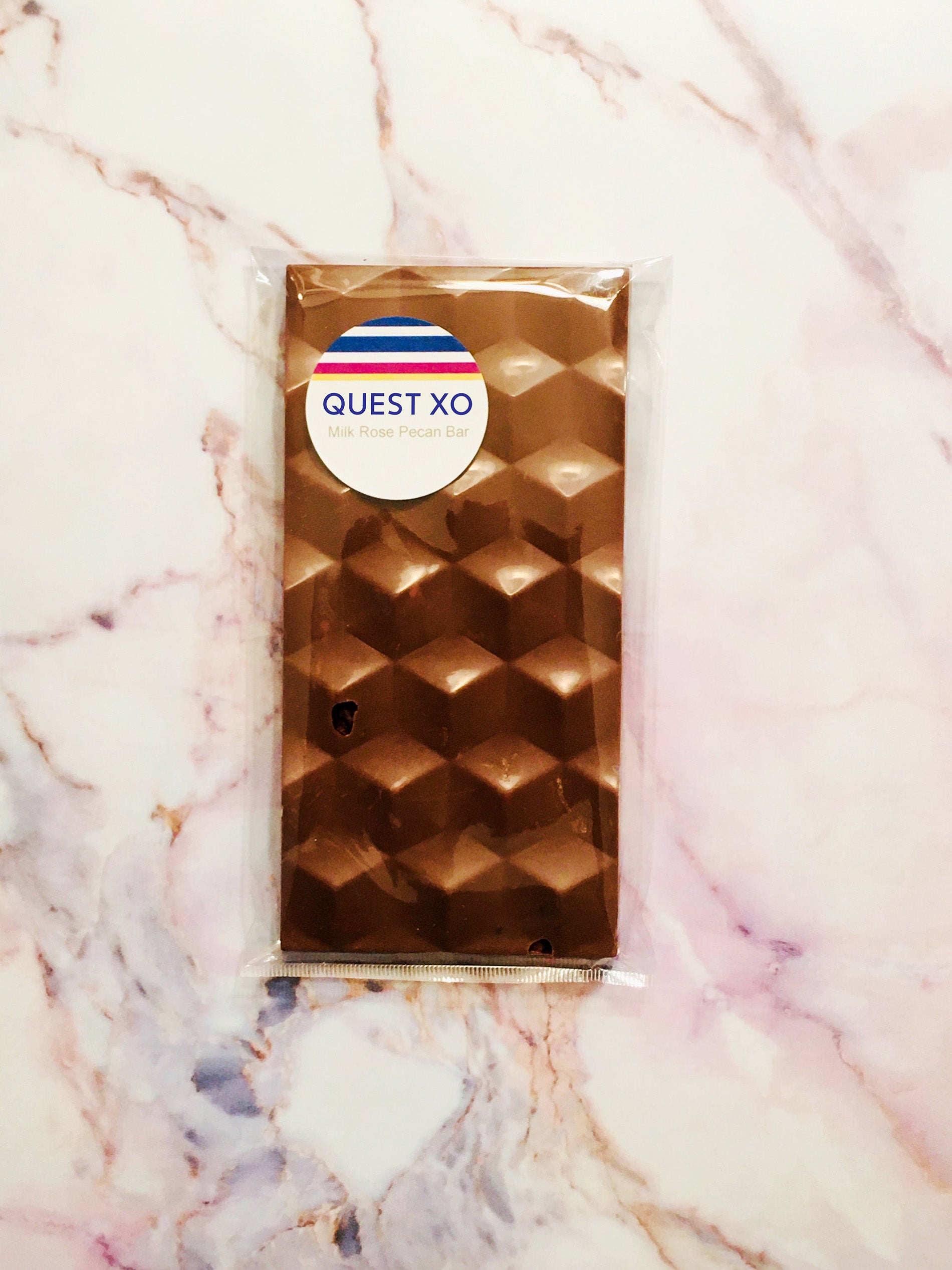 QUEST XO Rose Pecan Bar: Chocolate bar wrapped in a plastic wrapper with a marble background.